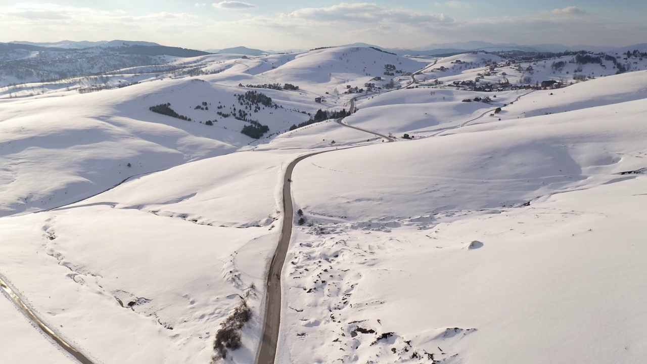 航拍的汽车沿着公路行驶，穿过塞尔维亚Zlatibor山的积雪覆盖的景观视频素材