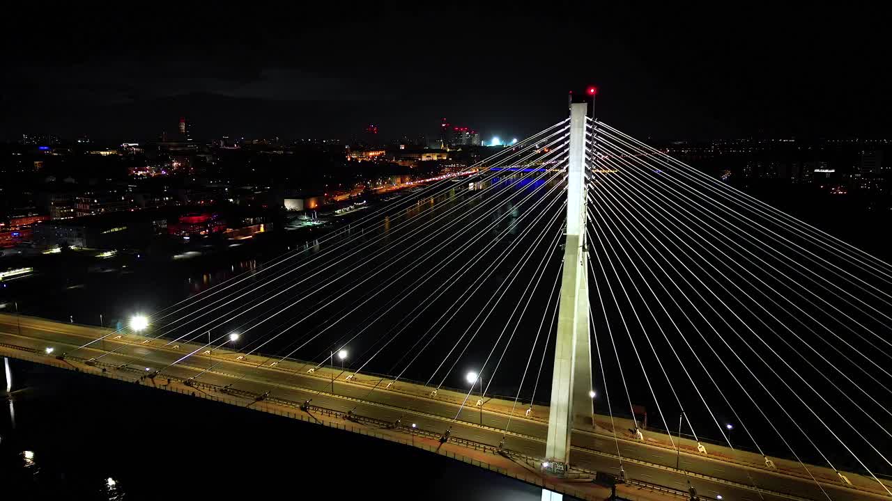 华沙城市景观的航拍全景。维斯瓦河上的斯韦托克日斯基吊桥，夜晚市中心的摩天大楼。电影城市全景天桥索桥塔视频素材