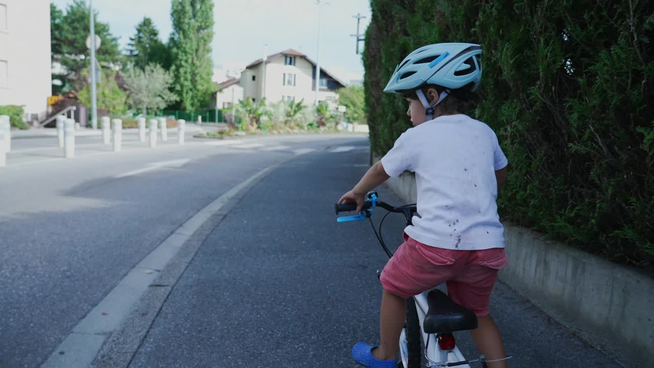 小男孩在城市街道上骑自行车。骑自行车的孩子戴着头盔在人行道上骑自行车视频素材