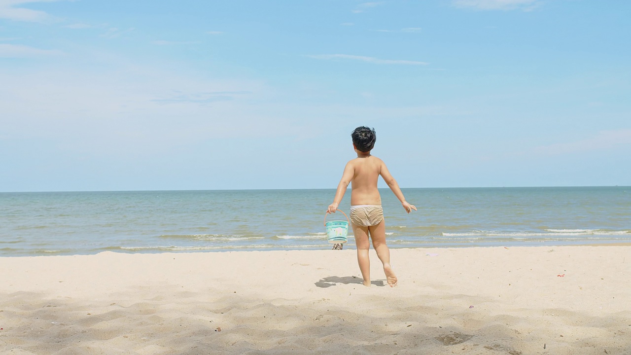 活跃快乐可爱的亚洲儿童男孩享受休闲暑假假期旅行在热带海洋海滩上散步，在阳光明媚的日子蓝天背景下玩沙视频素材