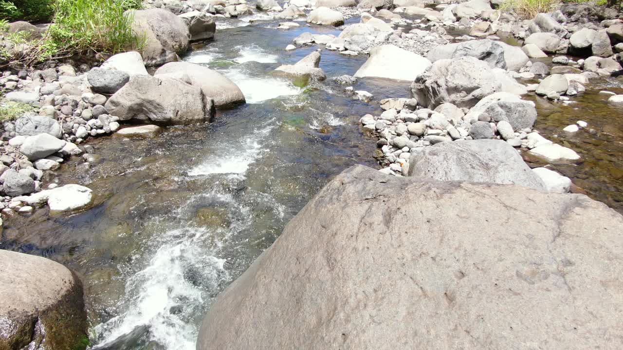 低空跟踪拍摄的是蜿蜒曲折的'Iao河谷河在岩石沉积物之间向下游流动。视频素材