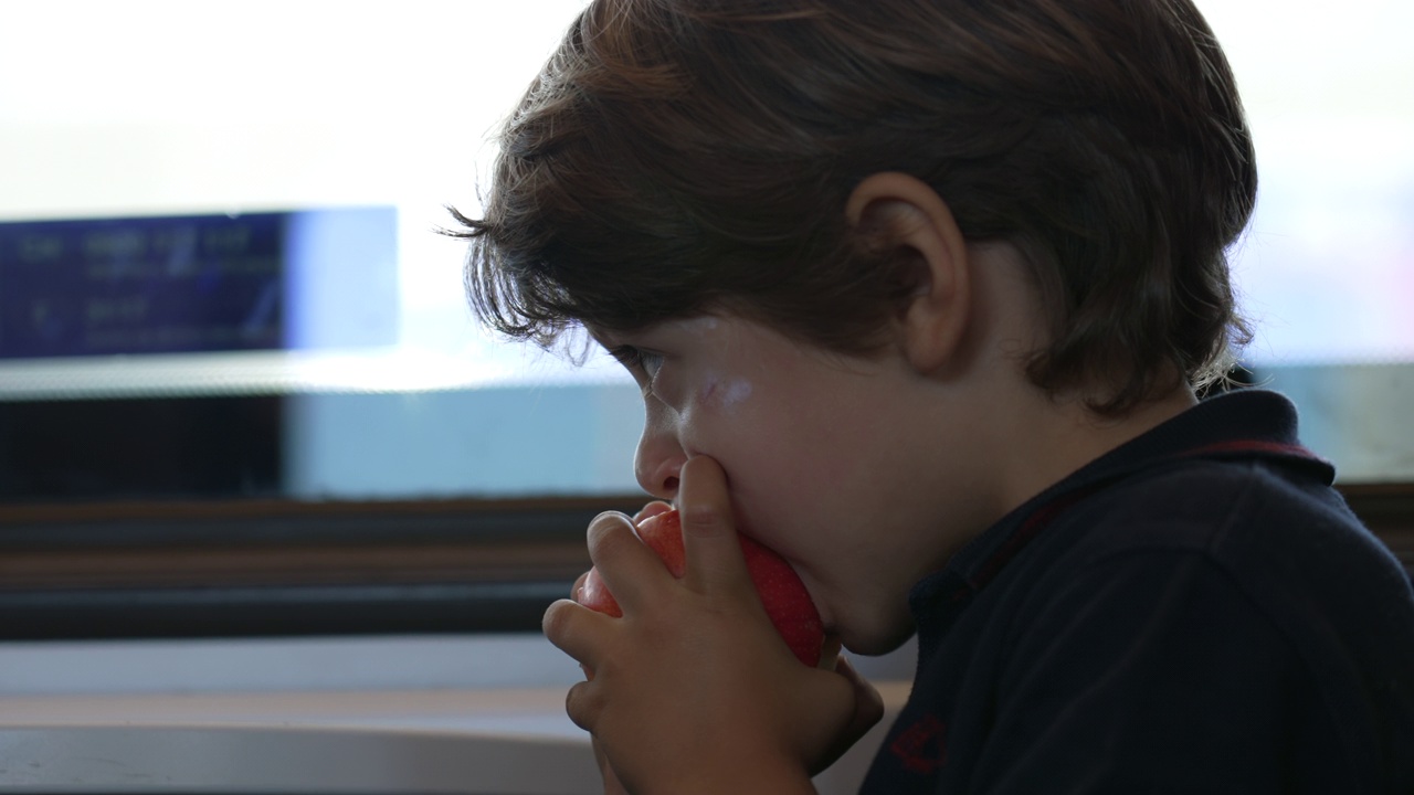 小男孩正在咬一口苹果。孩子吃健康的水果零食视频素材