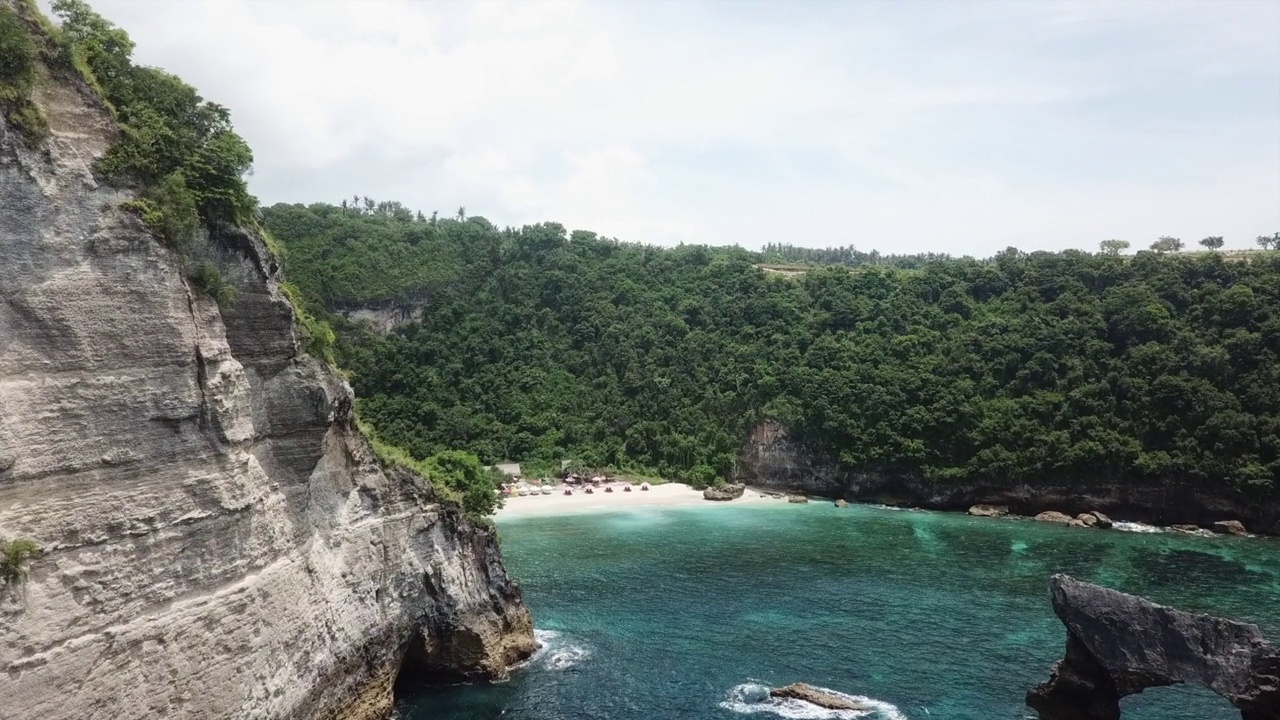 悬崖航拍揭示了印度尼西亚巴厘岛阿图海滩上的旅游小屋视频素材