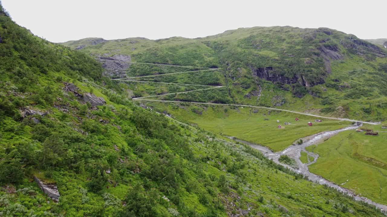 壮观的蜿蜒道路雕刻在山坡上，通往挪威的Vikafjell山口- Halsabakkane发夹弯-从远处的山坡上空中接近弯曲的道路视频素材