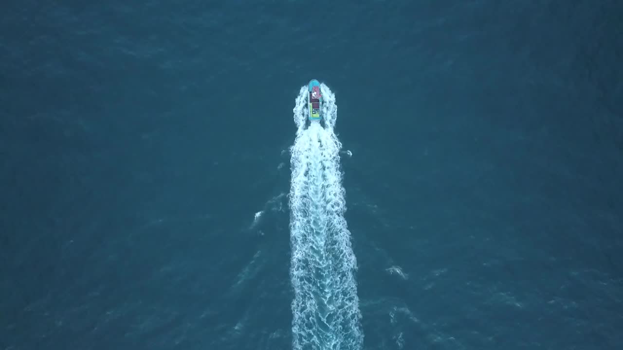 航拍的高清镜头，一艘船在海里游泳和多云天空下的海景视频素材