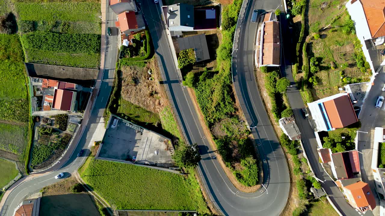 车辆行驶在弯曲的公路上，穿过房屋和田地视频素材