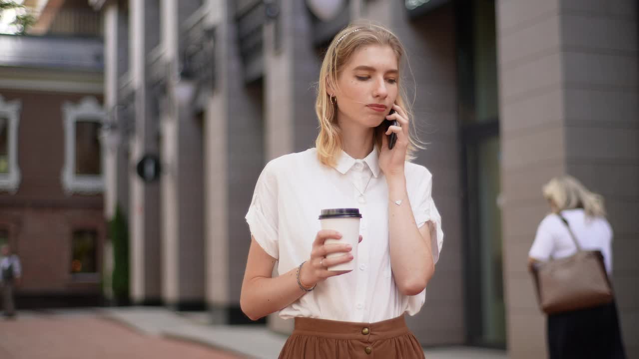 美丽的年轻女子站在户外，拿着咖啡和打电话的肖像。优雅时尚的女学生与咖啡聊天视频素材