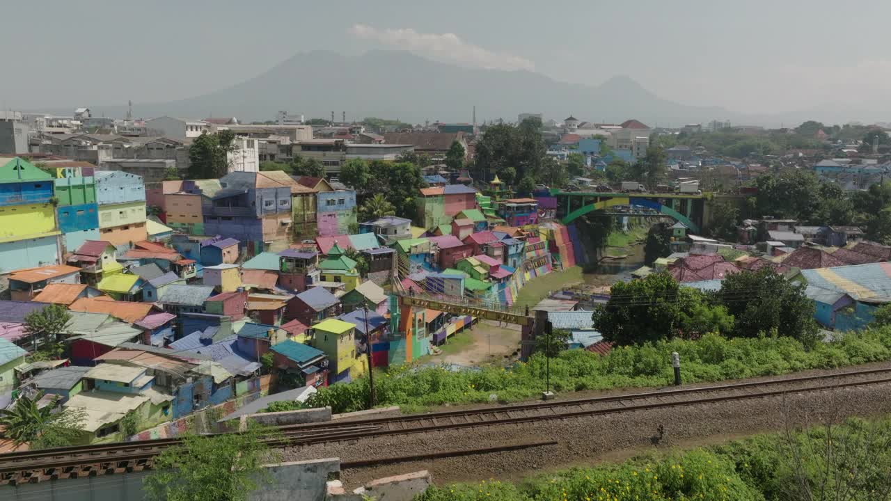 鸟瞰村里五颜六色的房子，无人机在铁路轨道上向前飞行-印度尼西亚爪哇视频素材