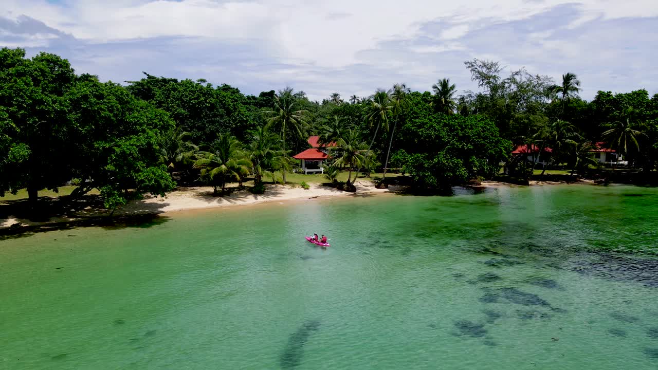 在泰国的一个热带岛屿上，一对夫妇划着皮艇，绿蓝turqouse色的Koh Mak海洋视频素材