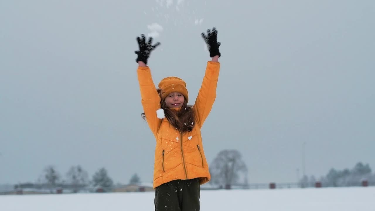 一个快乐的少年享受着雪。女孩在雪地里打转，抓雪。视频素材