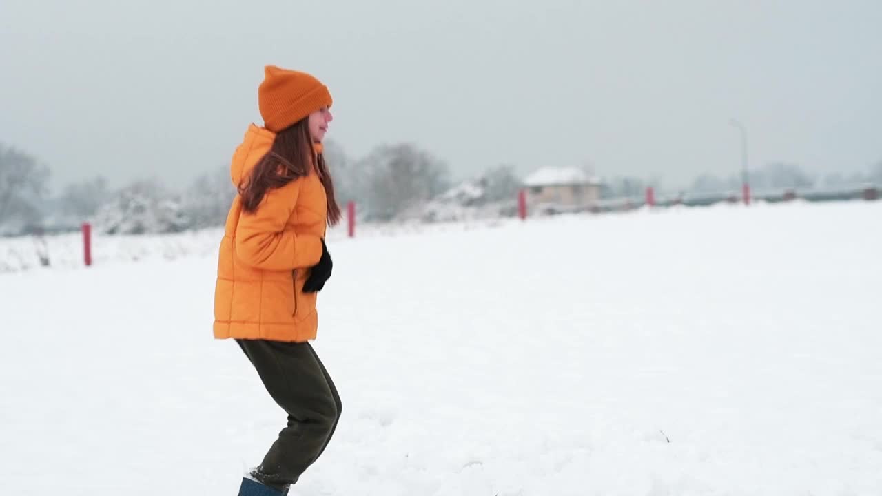 一个快乐的少年享受着雪。女孩在雪地里打转，抓雪。视频素材