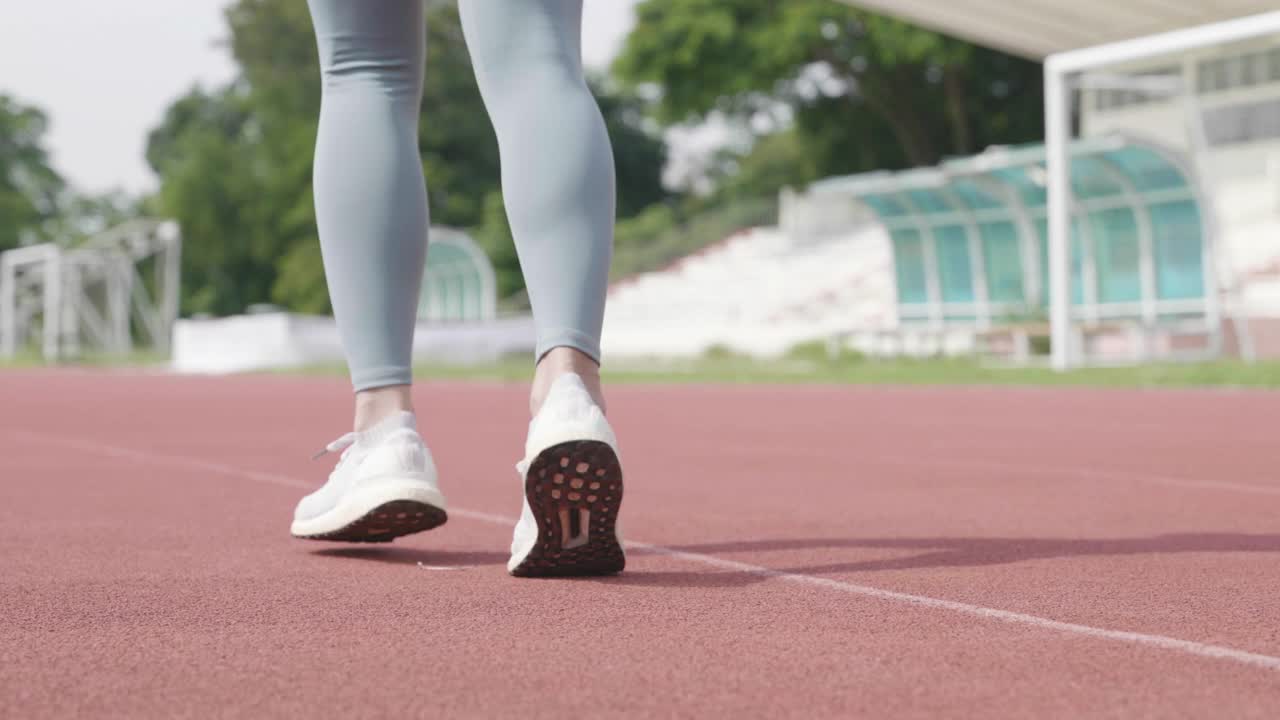 年轻女子在体育场慢跑的场景视频素材