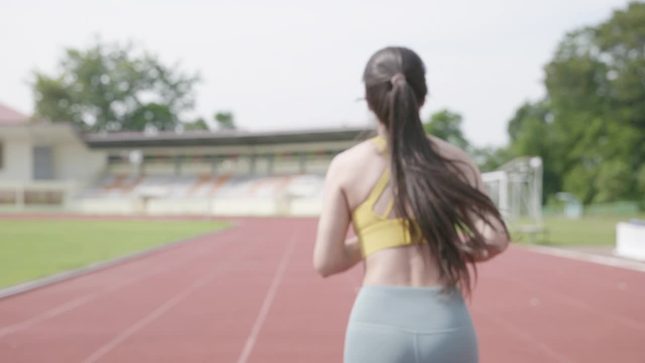 年轻女子在体育场慢跑的场景视频素材