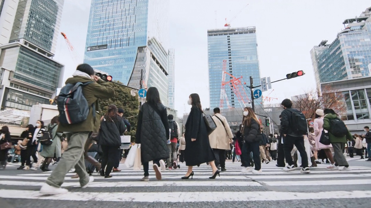 人群走过涩谷十字路口，低角度观看慢动作。东京旅游景点地标、交通交通、日本旅游、亚洲交通、亚洲城市生活理念视频素材