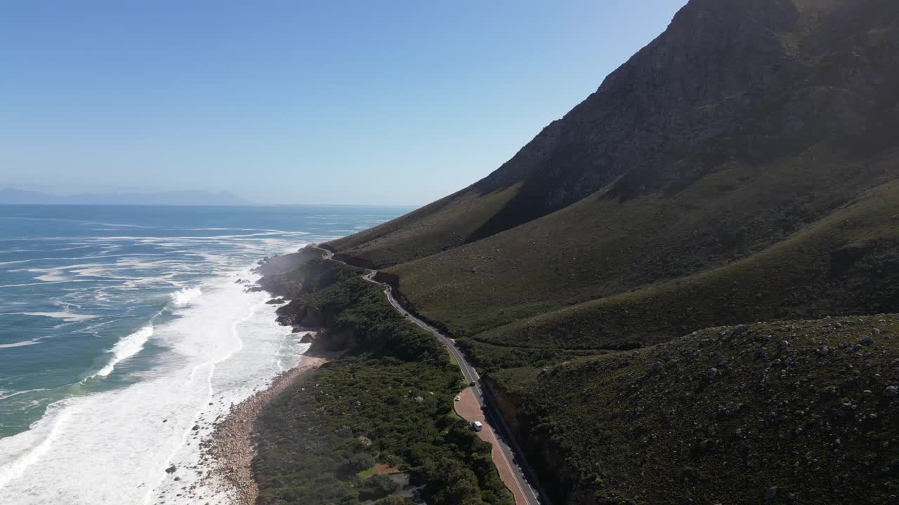 空中的泡沫般的海浪拍打着沙滩，背景是大山视频素材