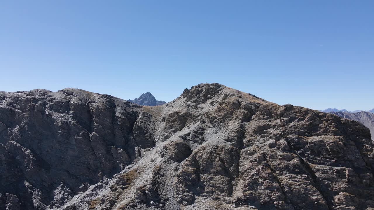 无人机拍摄的一个徒步旅行者站在岩石山峰上视频素材