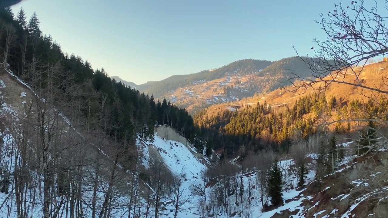 在明亮温暖的春天傍晚，在日落时分，在登山小径上的登山杆与白雪皑皑的高加索山脉全景放大。雪融化，春天来临视频素材