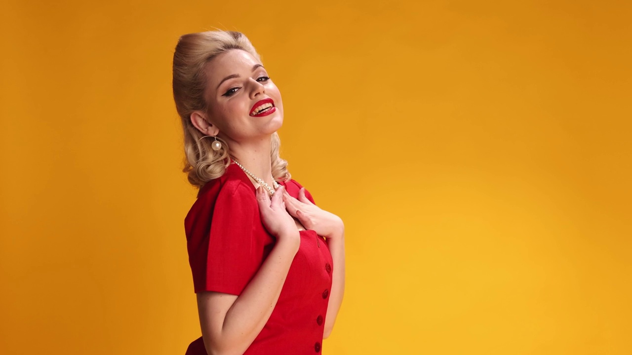 发送吻。美丽的金发女孩红唇化妆，时尚的发型在黄色的工作室背景摆姿势。美女风格视频素材画面2