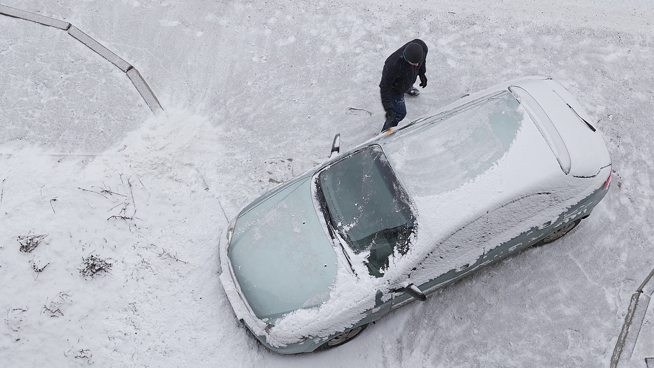 司机在出发前用刷子把车上的雪刷干净。从上面看。视频素材