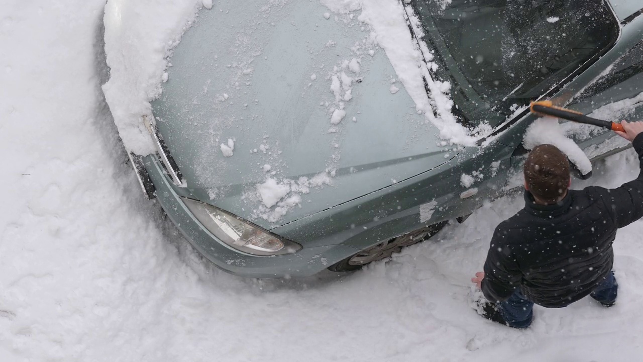 司机在出发前用刷子把车上的雪刷干净。从上面看。视频素材