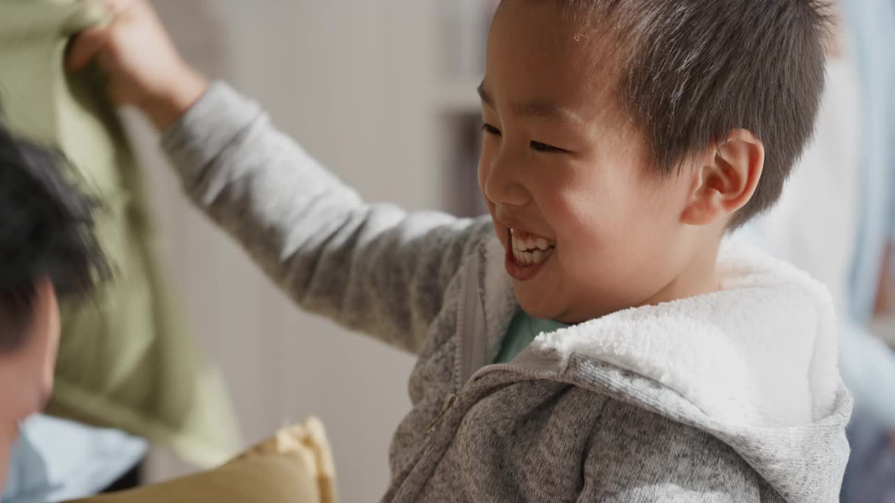 有趣的亚洲小男孩笑着和家人玩枕头大战，和父母在家里玩疯狂的游戏，一起玩4k视频素材