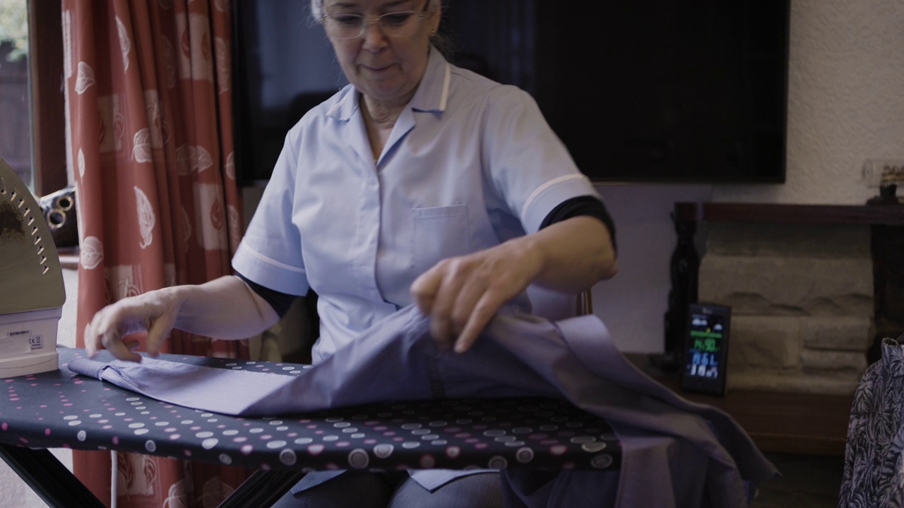 年长的妇女，熨烫和家务工作与退休，谈话，家政与洗衣和春季大扫除。在养老院的卫生，管家或护理人员，帮助和健康的生活方式视频素材画面4