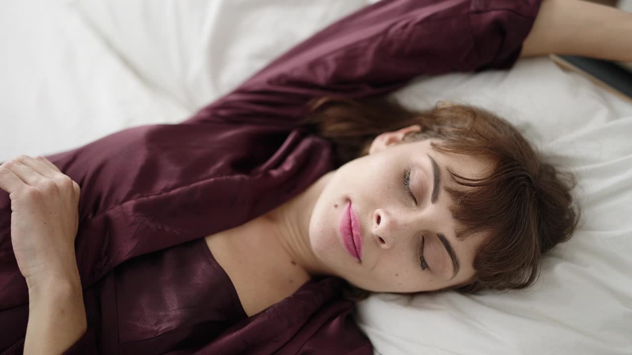 年轻的白人女人睡在床上，卧室里有睡衣视频素材