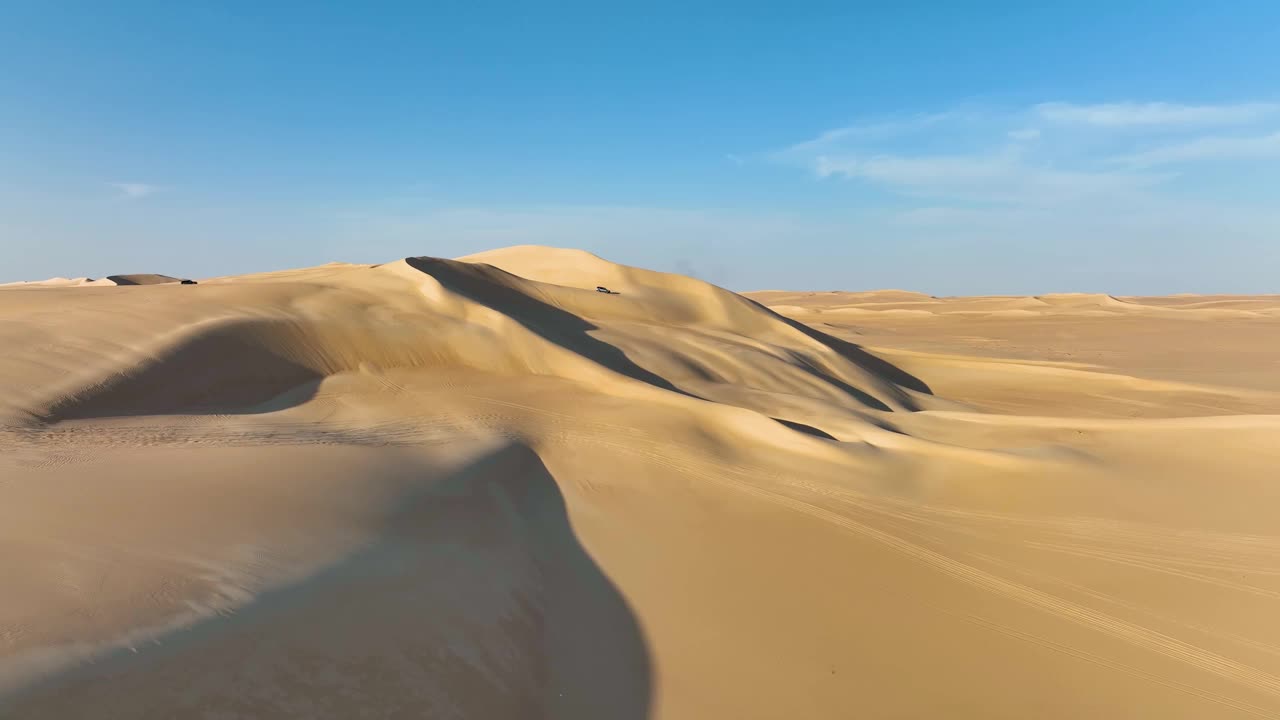 一组越野旅游车辆在埃及西部沙漠的沙丘顶部排成一行，因为他们准备进行陡峭的下降。视频素材