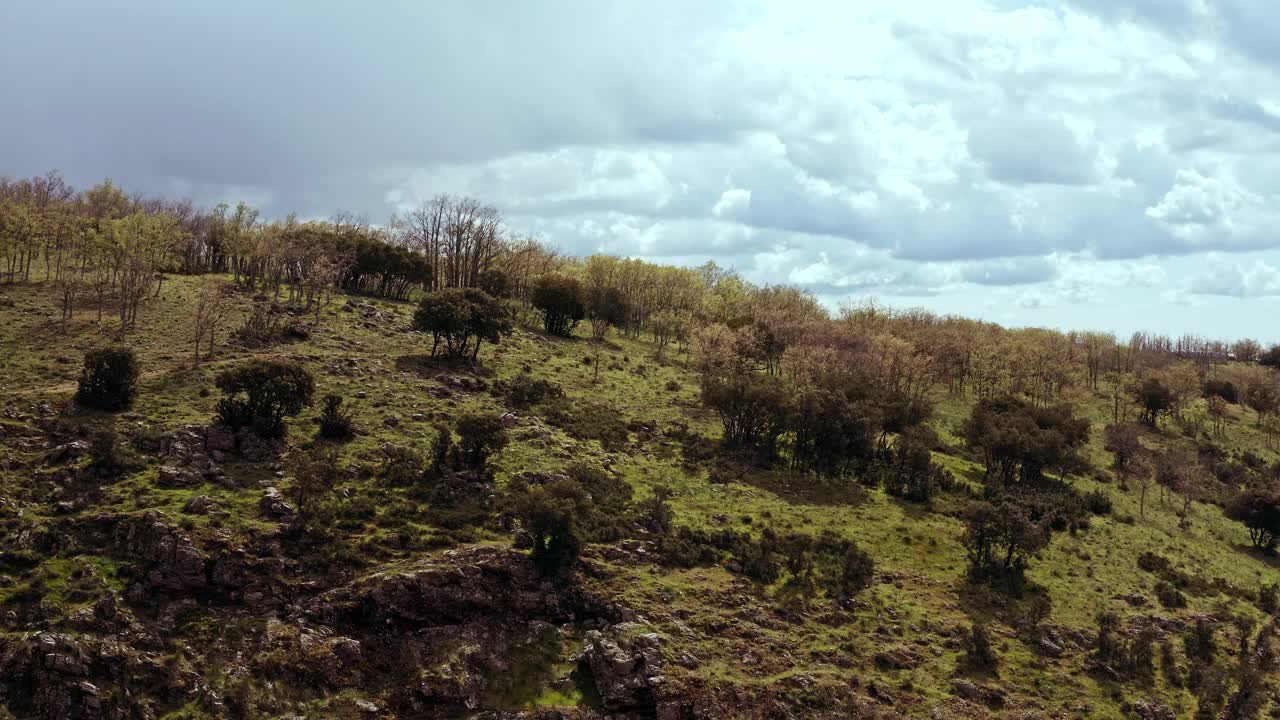 视频用无人机记录了秋天的山地景观，太阳在暴风雨云层、树木、植物和岩石之间。视频下载