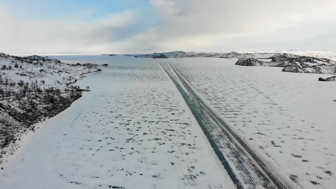 冰冻的贝加尔湖，被白雪覆盖。汽车沿着结冰的道路驶向奥尔洪岛。在冰湖上的冬季旅行。视频素材