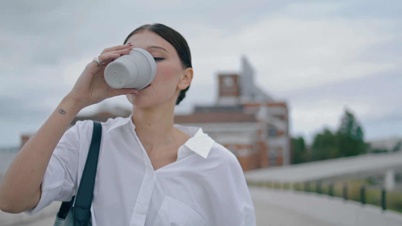 女孩喝咖啡外卖步行街特写。女商人喜欢散步视频素材