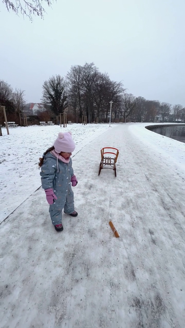 白人小女孩，穿着保暖的衣服拉着雪橇视频素材