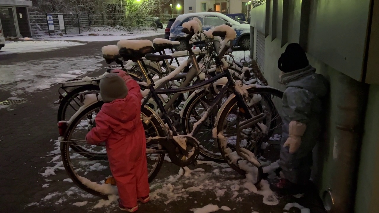 还在蹒跚学步的白人姐妹，从雪地里清理自行车视频素材