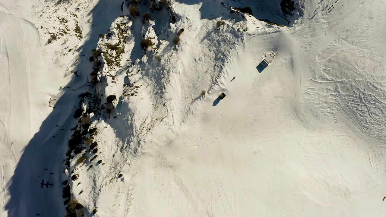 从上往下拍摄，沿着滑雪场边缘被雪覆盖的山脊飞行视频素材