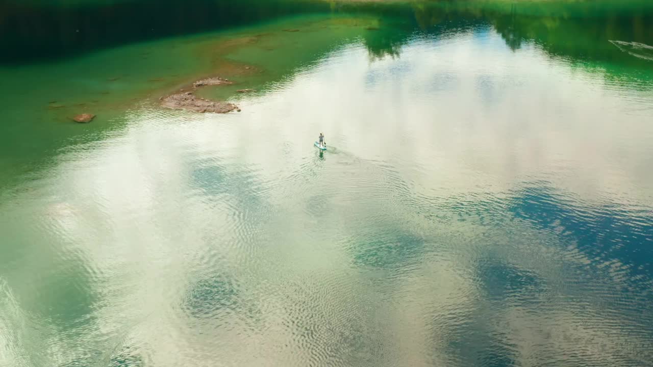 在湖中央的冲浪板或冲浪板上游泳的人视频素材