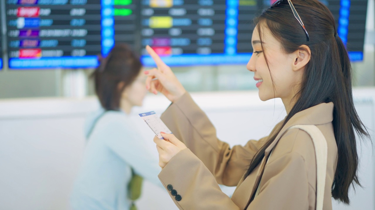 亚洲年轻女乘客在机场检查登机牌。迷人美丽的女游客朋友心情愉快，兴奋地乘飞机出国旅游度假旅行。视频素材