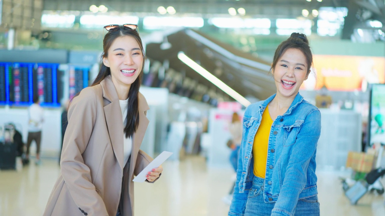 亚裔女性站在机场候机厅的登机口。迷人美丽的女游客旅客感到快乐和兴奋，去国外旅游的飞机假期旅行。视频素材