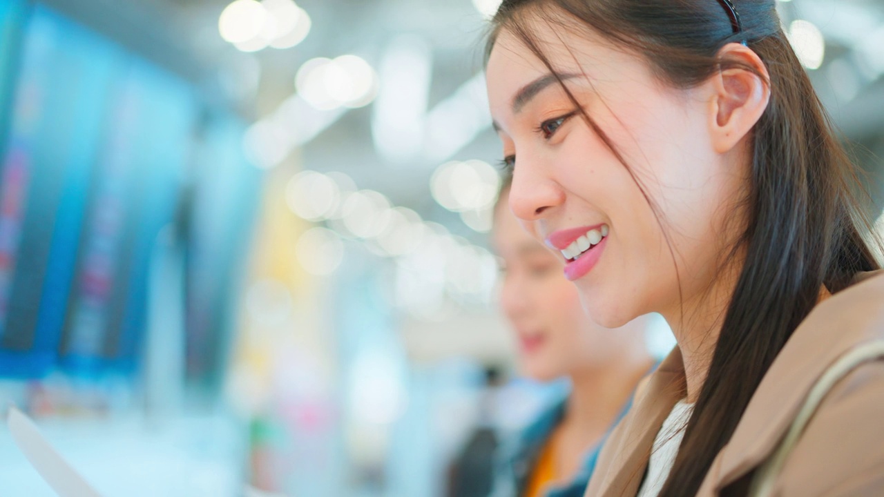 亚洲年轻女乘客在机场检查登机牌。迷人美丽的女游客朋友心情愉快，兴奋地乘飞机出国旅游度假旅行。视频素材