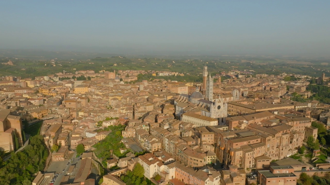 空中平移拍摄著名的Duomo Di Siena教堂在阳光明媚的一天在城市的房子视频素材