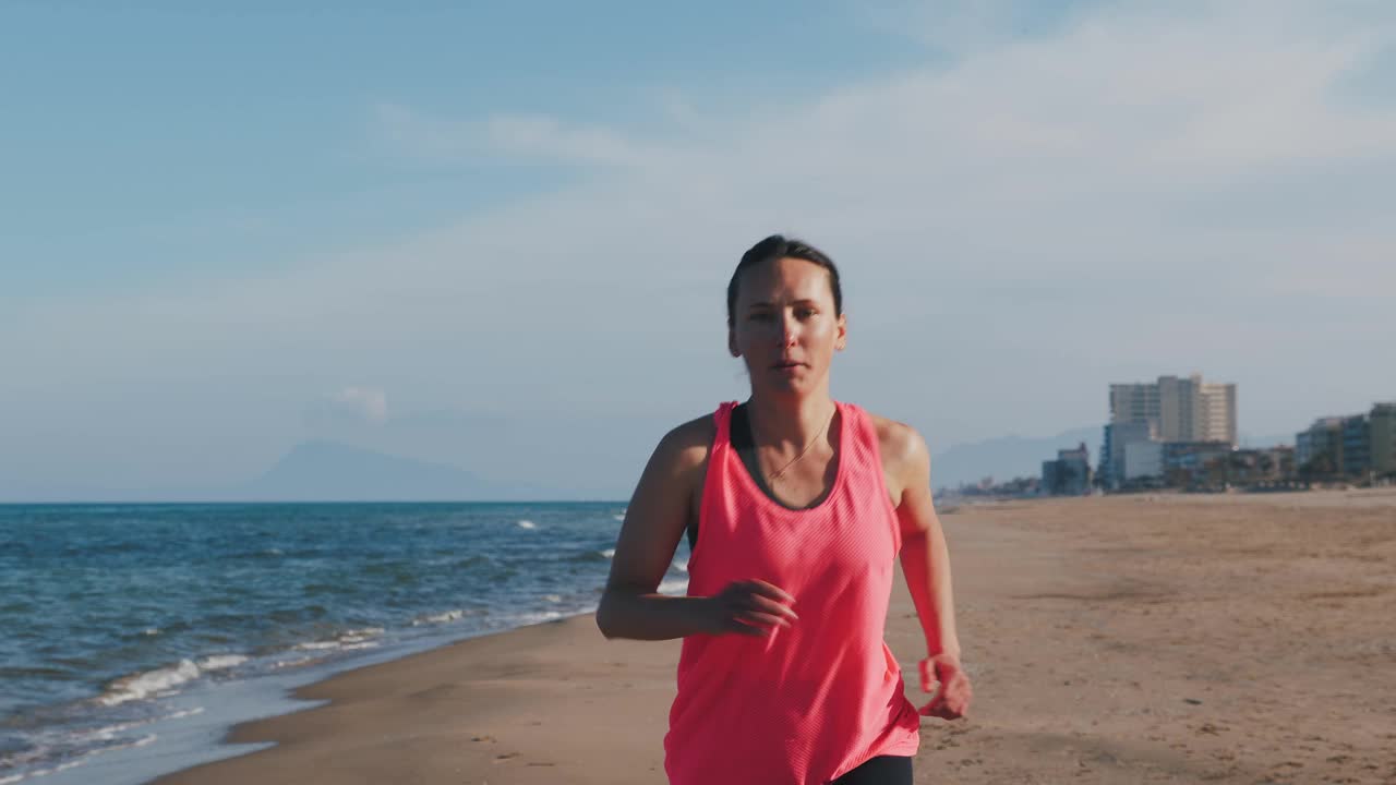 自信积极的年轻女子在海边沿着海滩跑步的肖像视频素材