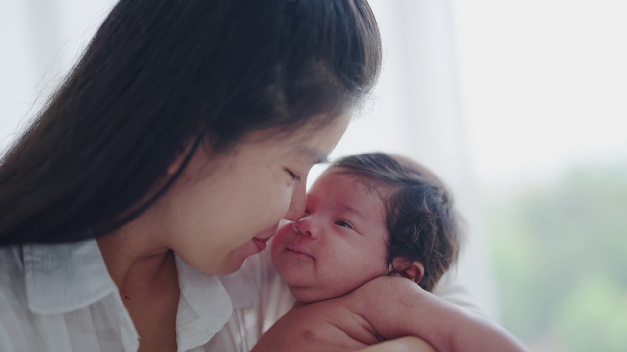 新生的婴儿被他的妈妈抱着亲吻。视频素材