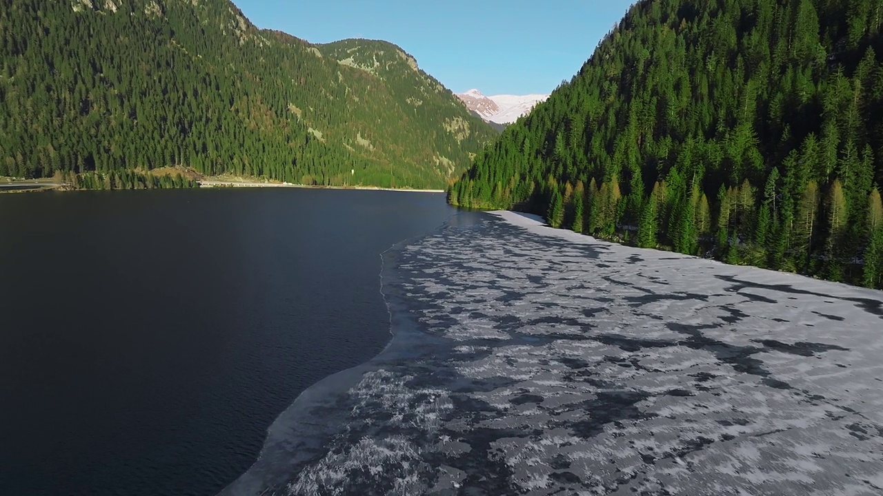 鸟瞰图的雪岩悬崖与森林在湖边。戏剧性和风景如画的场景。视频素材