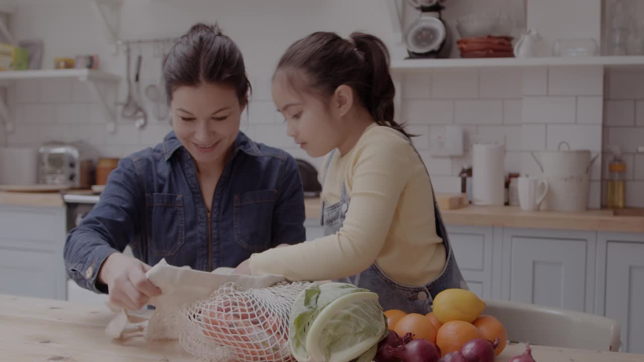 母亲和女儿在厨房里打开食品杂货视频素材