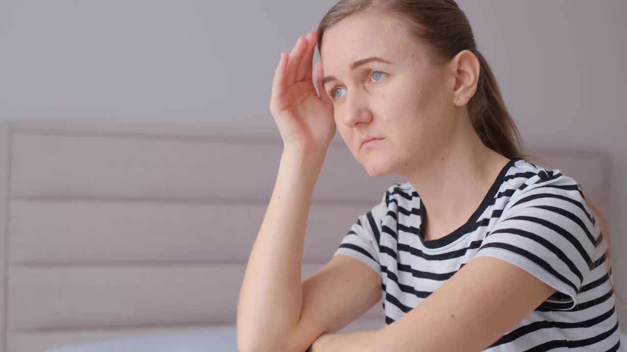 一位迷人的年轻女子坐在家里客厅的沙发上，感到头痛视频素材