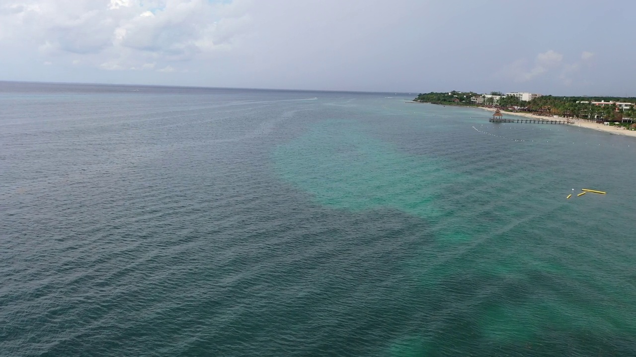 在墨西哥科苏梅尔的加勒比海，无人机飞过蓝绿色的海水，沿岸有酒店和沙滩视频素材