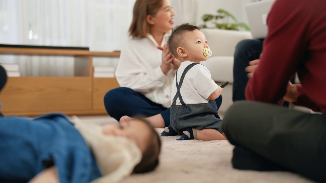 亚裔老人和女外孙坐在客厅的地板上，为鼓励婴儿鼓掌。视频素材