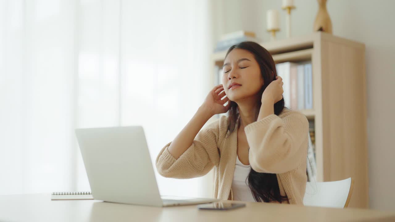 办公室综合症。劳累过度的年轻亚洲妇女感觉头痛，电脑笔记本电脑工作后视力问题。压力大的年轻女性在家里饱受疲劳之苦视频素材