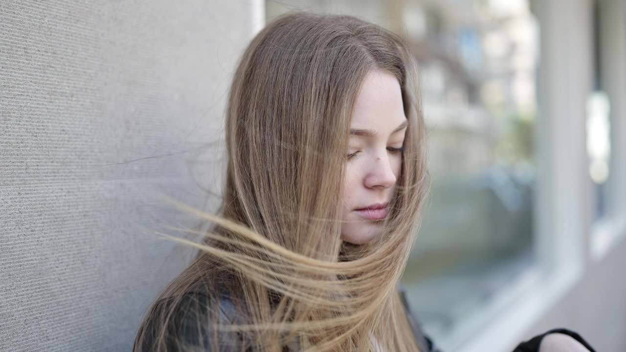 年轻的金发女子看着一边严肃的表情在街上视频素材