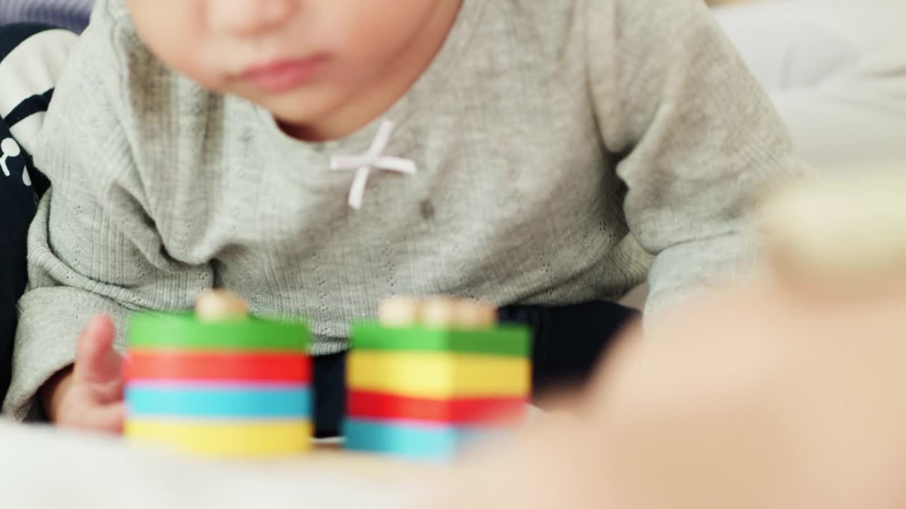 亚洲妈妈和小女孩正在床上学习玩彩色的木制玩具视频素材