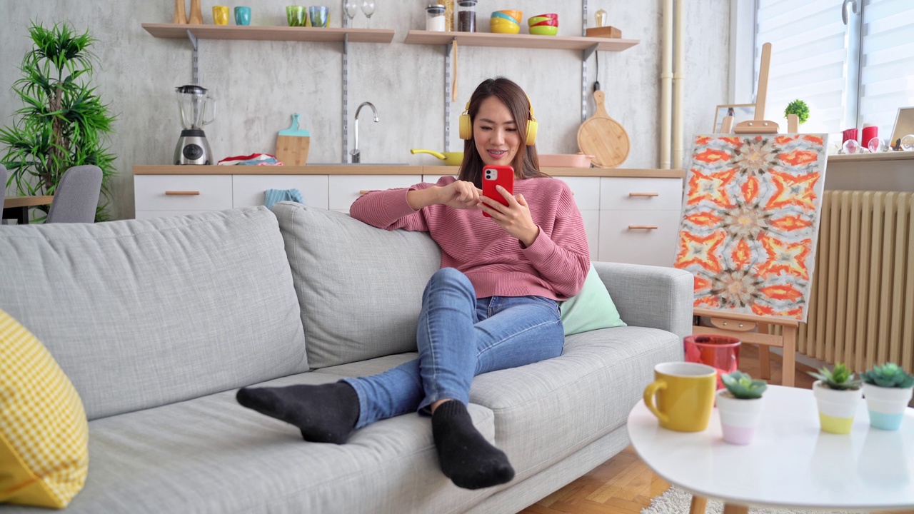 年轻女子在家里的沙发上听音乐视频素材